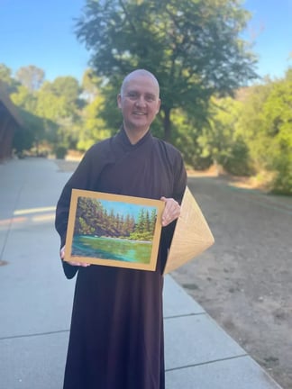 Br. Mindfulness holding up his painting and smiling